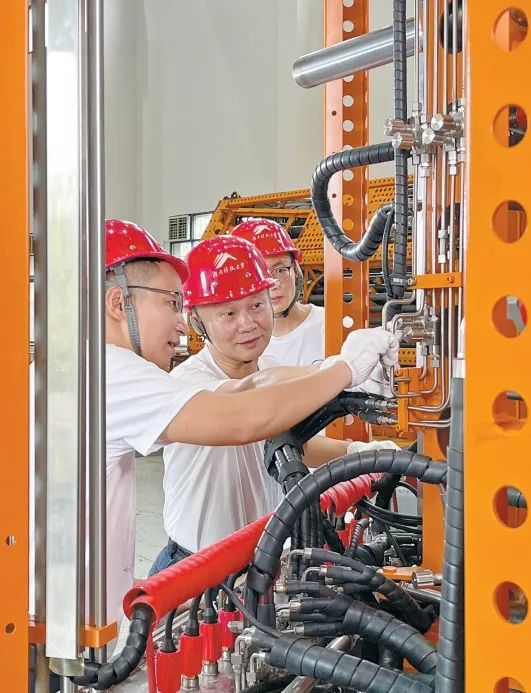  萬步炎（中）在湖南科技大學(xué)實(shí)驗(yàn)室調(diào)試設(shè)備。