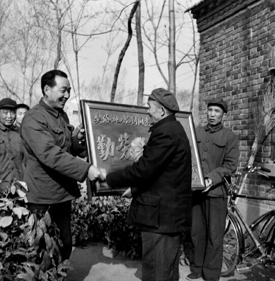 1978年，黨的十一屆三中全會(huì)召開，做出了對(duì)于當(dāng)代中國發(fā)展具有歷史性影響的重大決策，開啟了改革開放和集中力量進(jìn)行社會(huì)主義現(xiàn)代化建設(shè)的歷史新時(shí)期。圖為1982年，時(shí)任河南省鄢陵縣縣長(zhǎng)吳德榮上門為該縣第一個(gè)“萬元戶”頒發(fā)勞動(dòng)光榮匾。