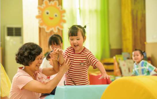 近年來，各地著力解決3歲以下嬰幼兒家庭入托難、入托貴等 問題，大力發(fā)展完善普惠托育服務(wù)體系，不斷增強人民群眾對普惠 托育服務(wù)的獲得感和滿意度，促進嬰幼兒健康成長。圖為2024年 9月4日，江西省奉新縣示范幼兒園托育班的老師和孩子們在快樂 地玩耍。